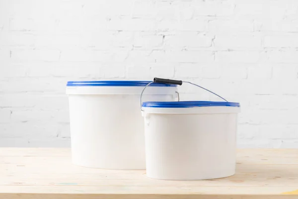 Dois baldes de plástico com tintas na superfície de madeira — Fotografia de Stock