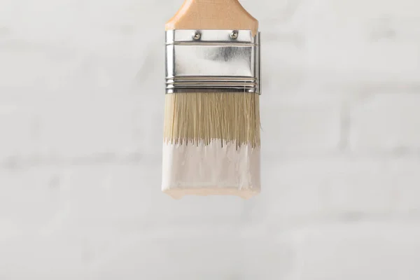 Ein Pinsel in weißer Farbe auf Ziegelwand — Stockfoto