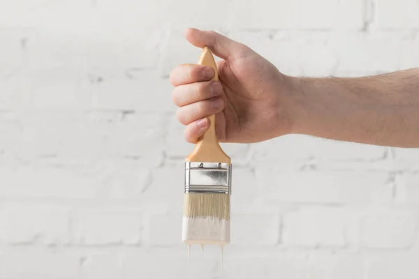 Cropped image of man holding brush in white paint — Stock Photo