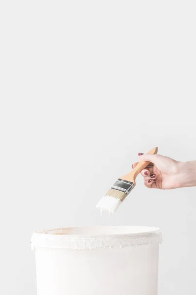 Imagem cortada de mulher segurando escova em tinta branca acima do balde isolado no branco — Fotografia de Stock