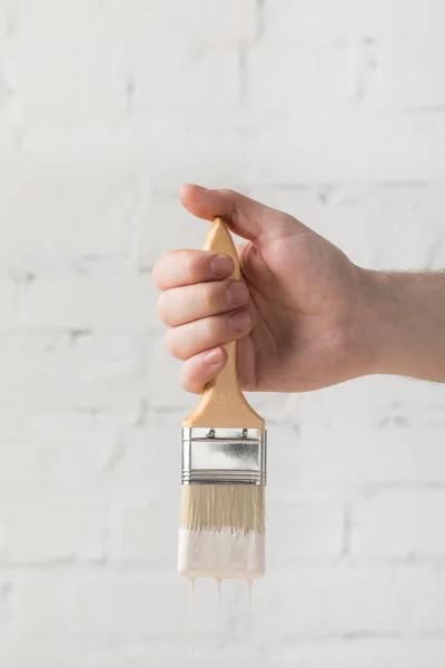 Cropped image of man holding brush in white paint — Stock Photo