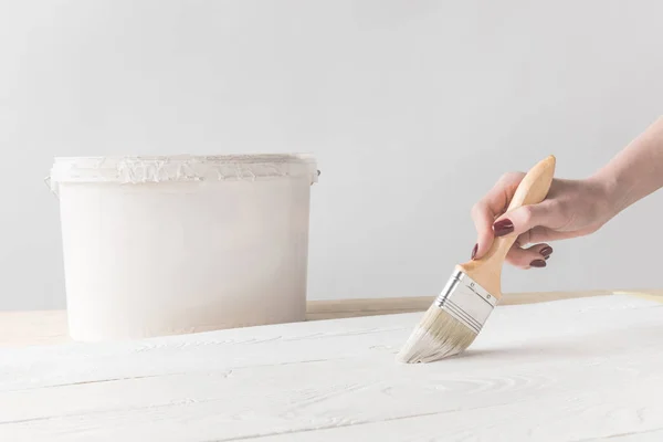 Immagine ritagliata di donna pittura superficie in legno con vernice bianca — Foto stock