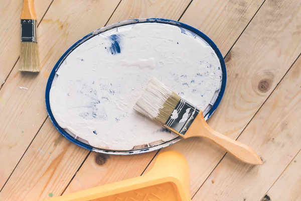 Top view of brush in white paint on cover from bucket — Stock Photo