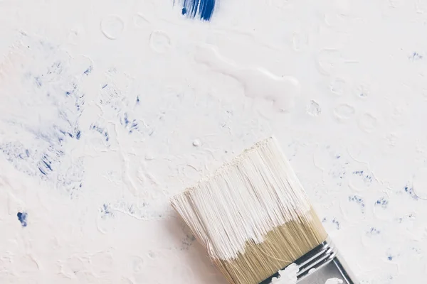 Top view of brush in white paint on cover from bucket — Stock Photo