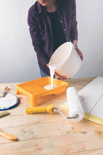 Immagine ritagliata della donna versando vernice bianca nel vassoio di plastica — Foto stock