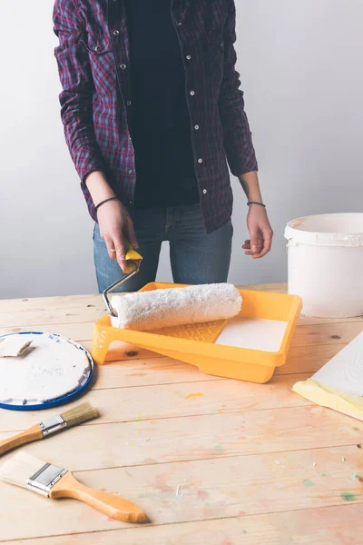 Imagem cortada de menina segurando pincel de rolo de pintura acima da bandeja com tinta — Fotografia de Stock