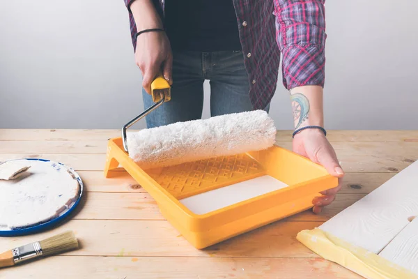 Cropped image of woman holding paint roll brush above tray with paint — Stock Photo