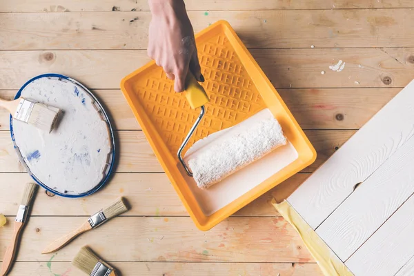 Cropped image of girl putting paint roll brush in white paint — Stock Photo