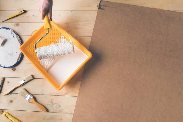 Imagen recortada de la mujer poniendo pincel rollo de pintura en pintura blanca - foto de stock