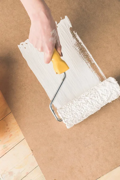 Cropped image of woman painting plywood with paint roll brush — Stock Photo