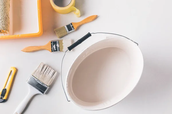 Top view of bucket with white paint and tools for repairs on surface — Stock Photo