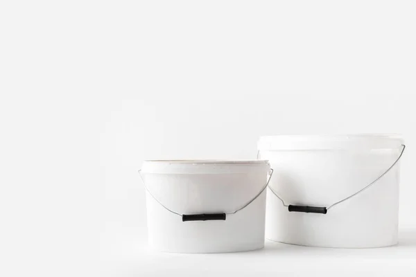 Dos cubos de plástico blanco con pinturas aisladas en blanco - foto de stock