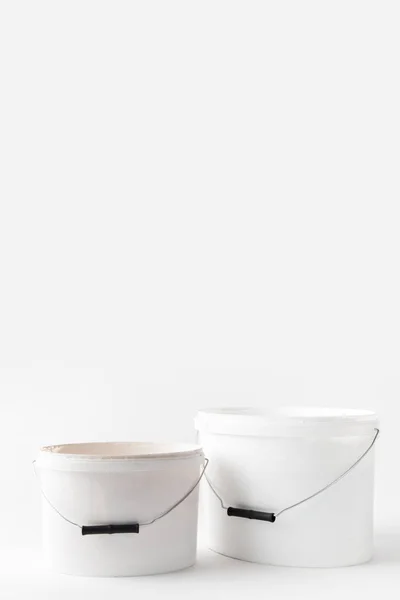 Dos cubos de plástico blanco con pinturas aisladas en blanco - foto de stock