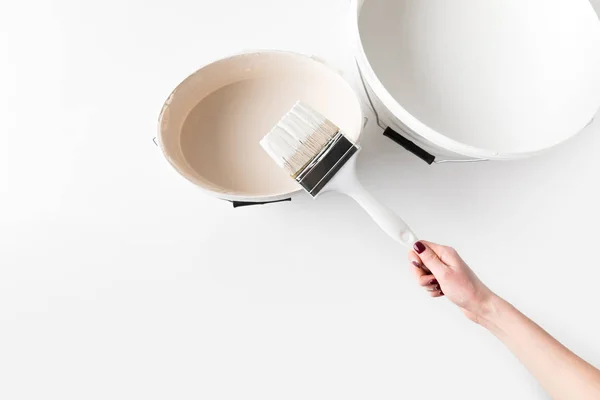 Cropped image of girl holding brush in white paint on bucket isolated on white — Stock Photo