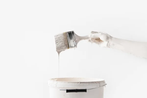 Imagem cortada de mulher segurando escova em tinta branca acima do balde isolado no branco — Fotografia de Stock