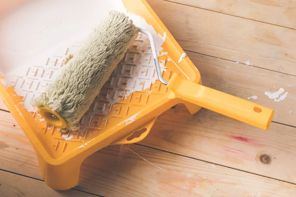 Rouleau de peinture brosse et peinture blanche dans un plateau en plastique — Photo de stock