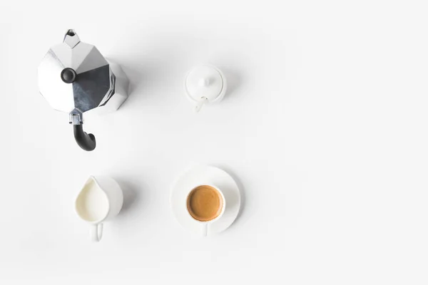 Vue de dessus de tasse de café arrangée, jag de lait et cafetière sur la surface blanche — Photo de stock