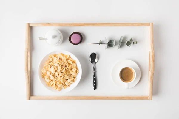 Vista superior del desayuno con copos de corcho en tazón y taza de café en bandeja en la superficie blanca — Stock Photo