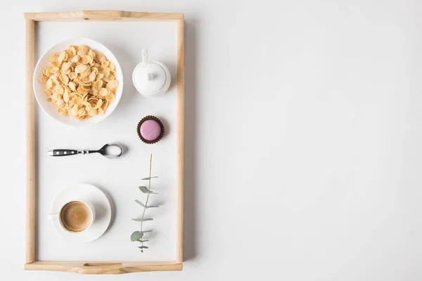 Vista superior del desayuno con copos de corcho en tazón y taza de café en bandeja en la superficie blanca — Stock Photo