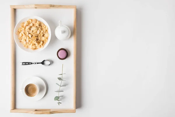 Vista superior del desayuno con copos de corcho en tazón y taza de café en bandeja en la superficie blanca - foto de stock