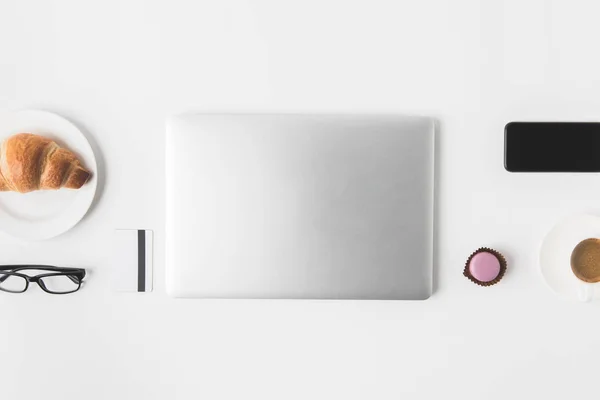 Tendido plano con dispositivos digitales, anteojos y desayuno sobre mesa blanca - foto de stock