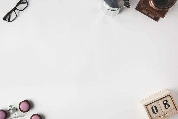 Vista dall'alto di disposizione di calendario, occhiali, dessert e caffettiera su superficie bianca — Stock Photo