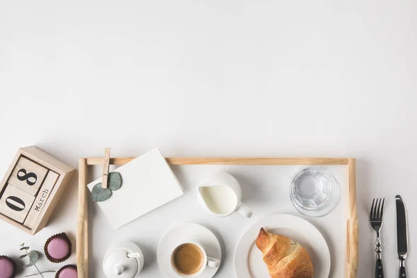 Posare piatto con tazza di caffè e croissant per la prima colazione su vassoio su tavolo bianco — Foto stock