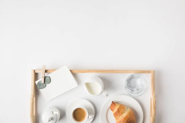 Acostado plano con café taza y croissant para el desayuno en bandeja en la mesa blanca — Stock Photo