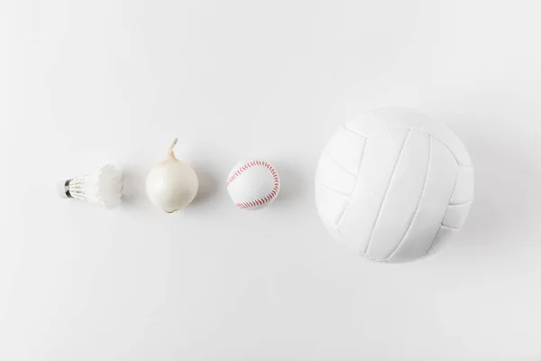 Various sports equipment andonion in row on white surface — Stock Photo