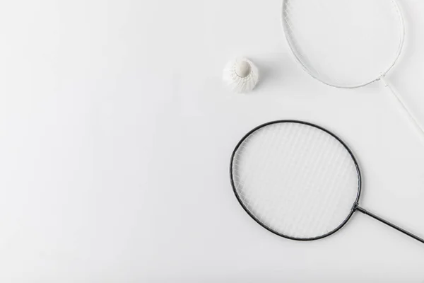 Top view of badminton rackets with suttercock on white surface — Stock Photo