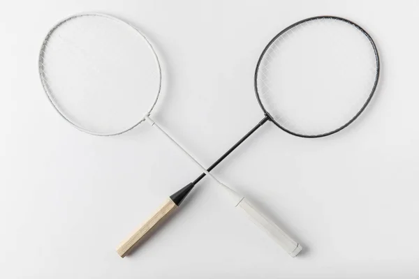 Top view of crossed badminton rackets on white surface — Stock Photo