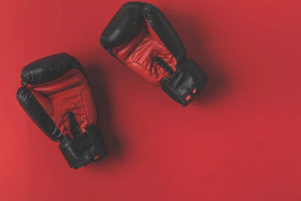 Vue du dessus des gants de boxe couchés sur le dessus de la table rouge — Photo de stock