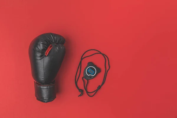 Vue du dessus du gant de boxe avec chronomètre sur plateau rouge — Photo de stock