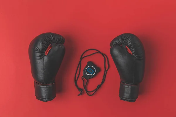 Вид зверху на боксерські рукавички з секундоміром на червоній стільниці — стокове фото