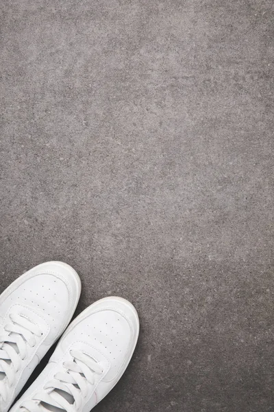 Vue de dessus des chaussures blanches élégantes sur la surface du béton — Photo de stock