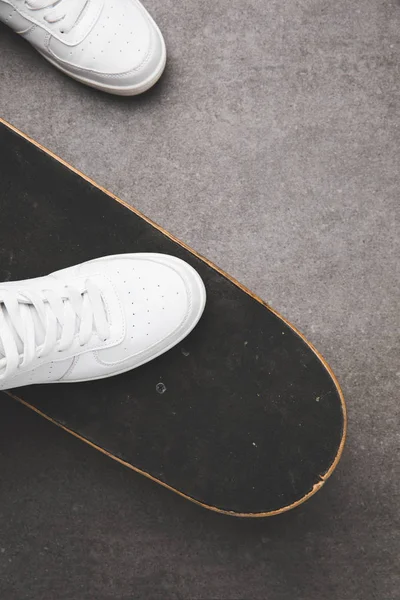Вид сверху на белую обувь на скейтборде на серой бетонной поверхности — стоковое фото