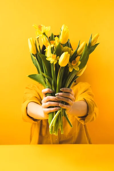 Close-up vista da menina segurando belas flores amarelas da primavera no amarelo — Fotografia de Stock