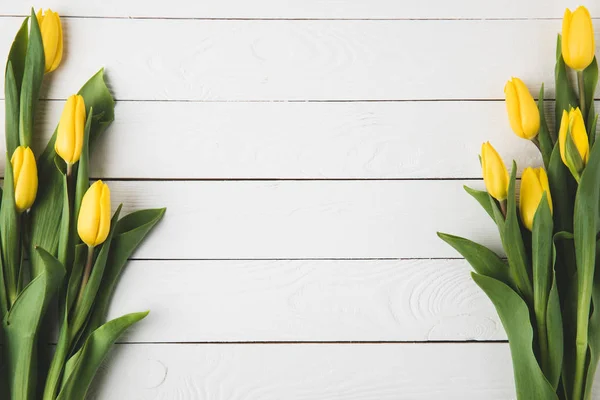 Vista superior de hermosas flores de tulipán amarillo en la superficie de madera blanca - foto de stock