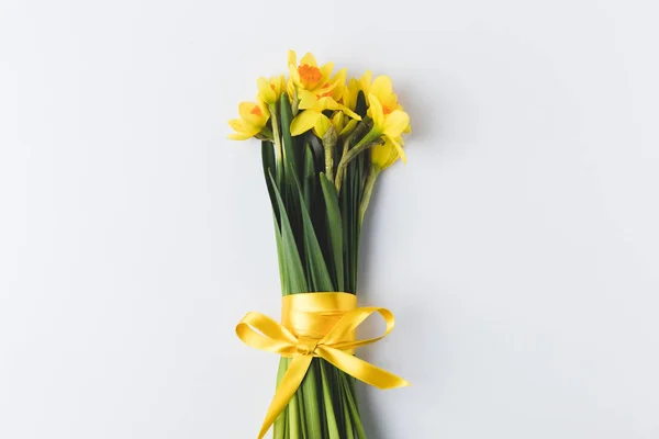 Beautiful blooming daffodils flowers with yellow ribbon isolated on grey — Stock Photo