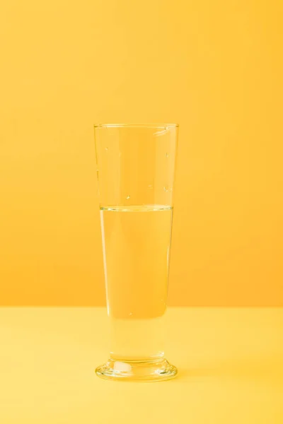 Close-up view of glass vase with water on yellow — Stock Photo