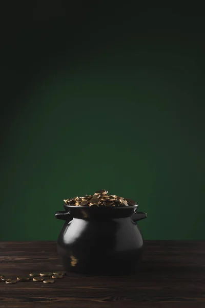 Pote preto de moedas de ouro na mesa de madeira em verde, st patricks conceito dia — Fotografia de Stock