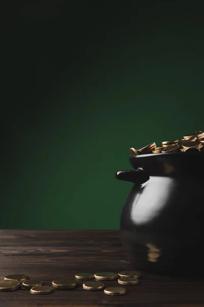 Pote preto de moedas de ouro na mesa de madeira em verde, st patricks conceito dia — Fotografia de Stock