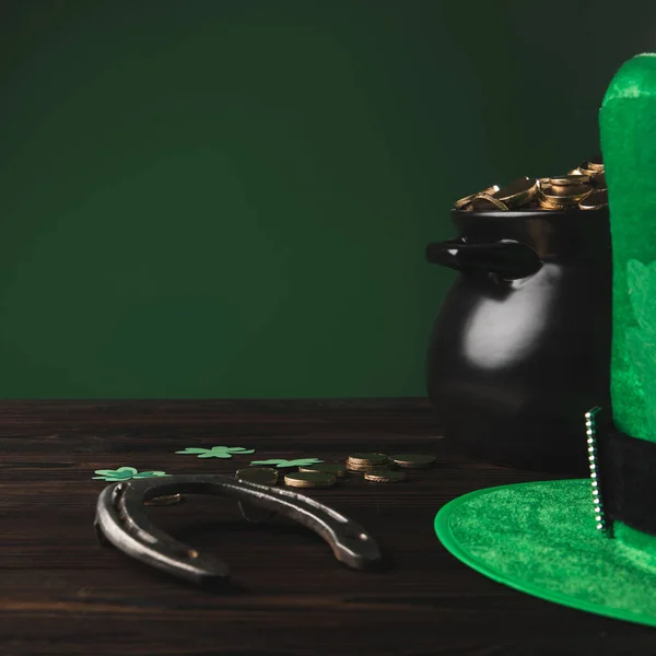 Golden coins, horseshoe and green hat on wooden table, st patricks day concept — Stock Photo