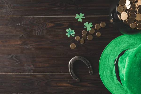 Vista dall'alto della pentola con monete d'oro, ferro di cavallo e cappello verde sul tavolo di legno, concetto giorno st patricks — Foto stock