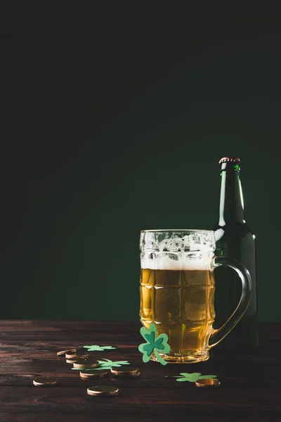 Vetro di birra con bottiglia e monete d'oro sul tavolo, concetto giorno st patricks — Foto stock