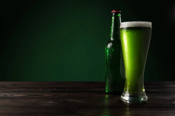 Vaso de cerveza verde con botella sobre mesa de madera, concepto de día de San Patricio - foto de stock