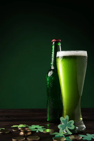 Botella de vidrio y vidrio de cerveza verde con monedas en la mesa, San Patricio concepto de día - foto de stock