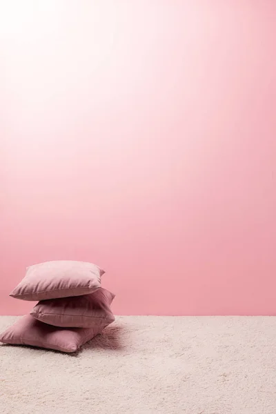Oreillers sur le tapis devant le mur rose — Photo de stock