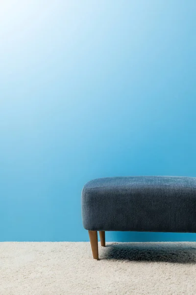 Pouf standing on carpet in front of blue wall — Stock Photo