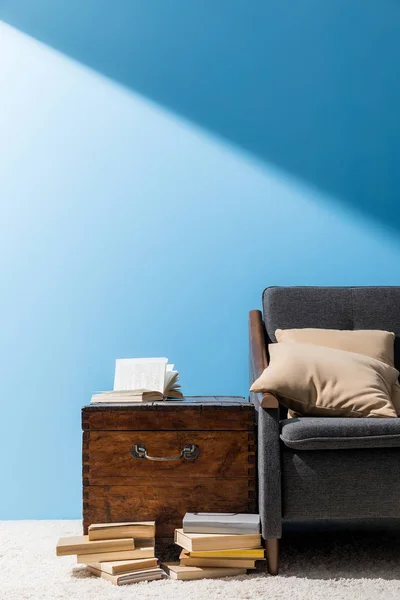 Coffre rustique avec des livres près du canapé devant le mur bleu — Stock Photo